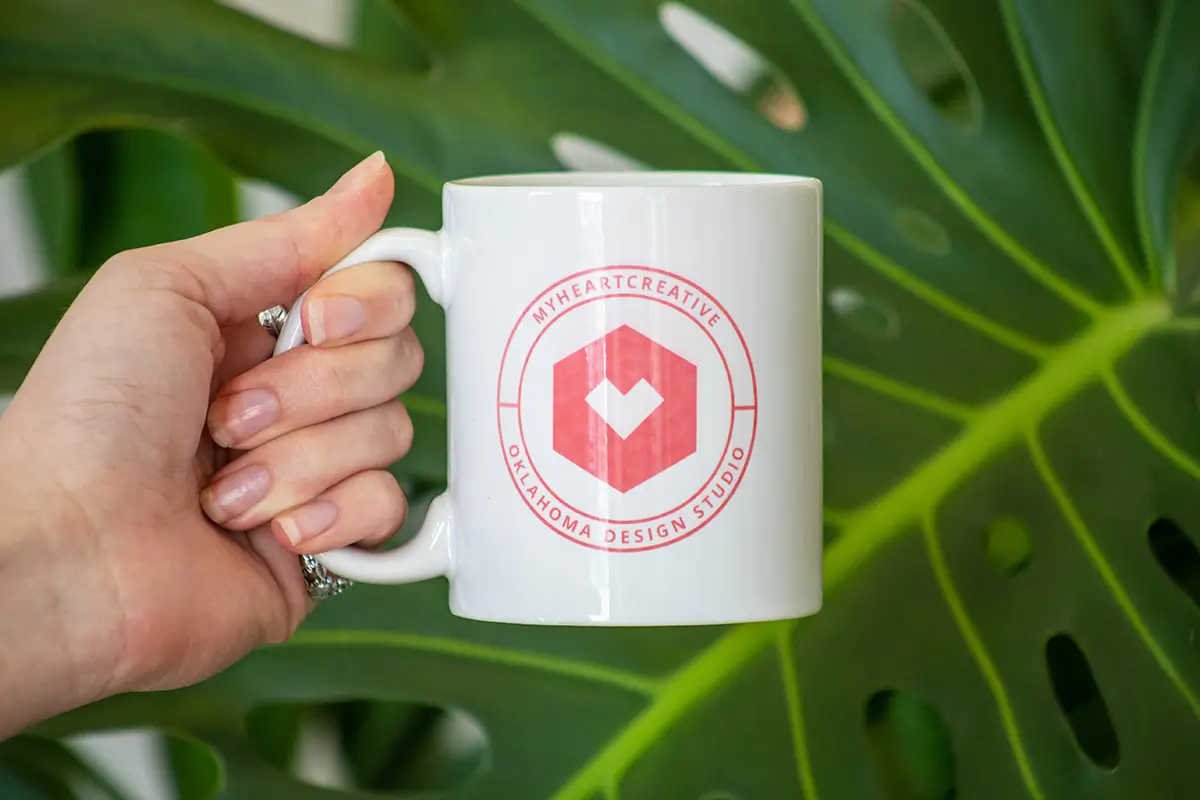 A hand holding a myheartcreative mug