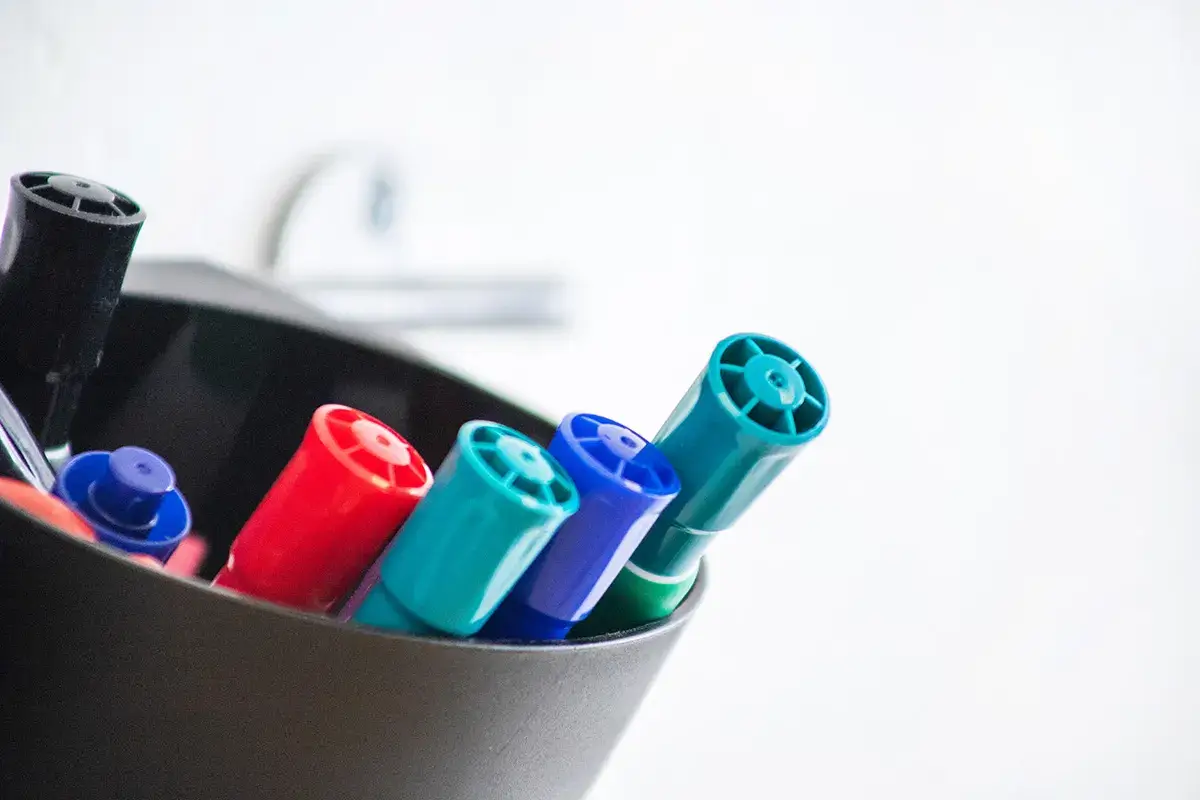 A cup holding multicolored dry erase markers